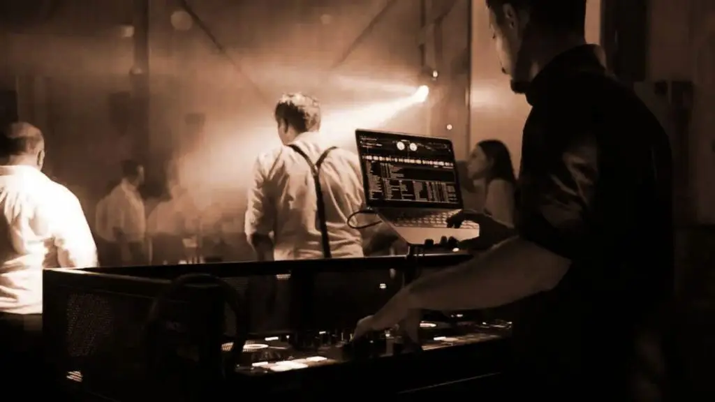 DJ Jonez am DJ-Pult, im Hintergrund feiernde Gäste